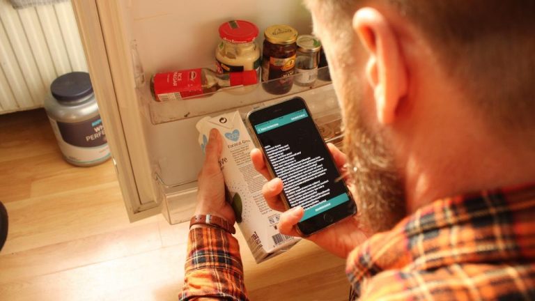 A picture of a person using Envision app on their smartphone to read details on a milk carton.