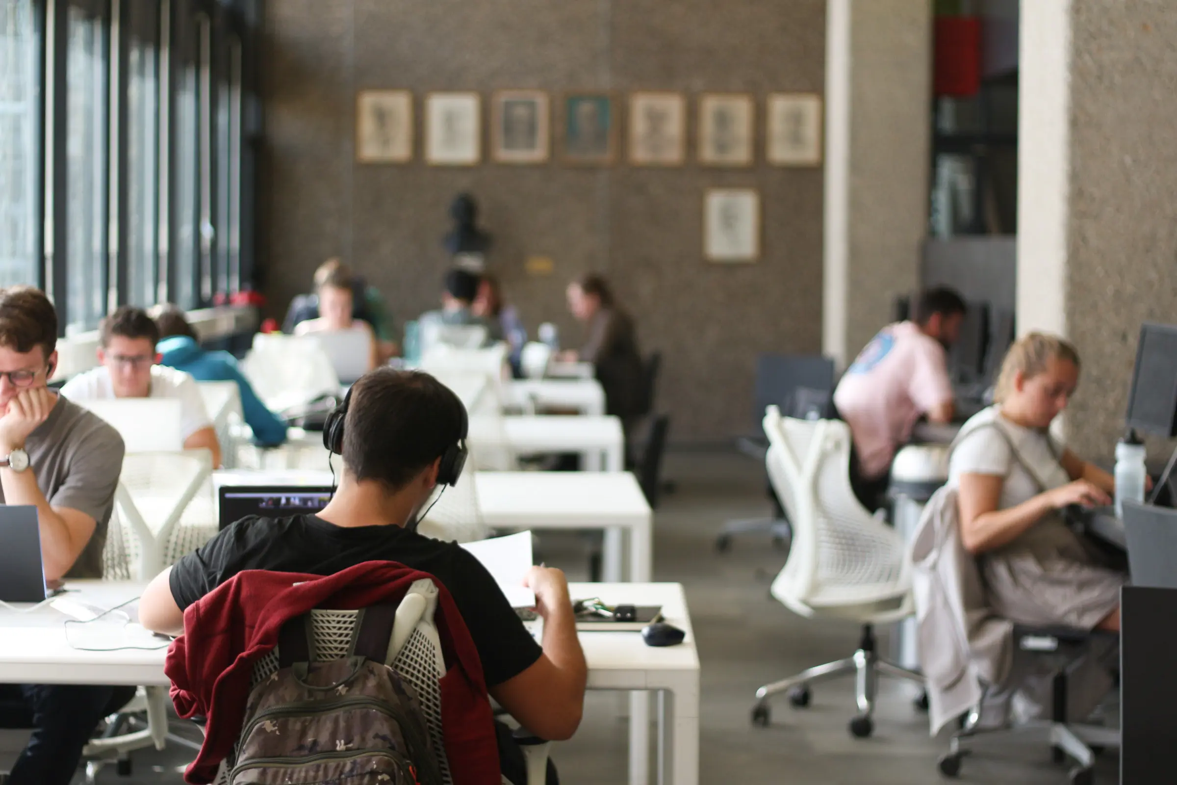 Studenten zitten aan bureaus. Ze studeren.