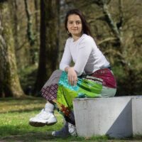 Sofia Ghigliani zit op een bankje en kijkt in de camera