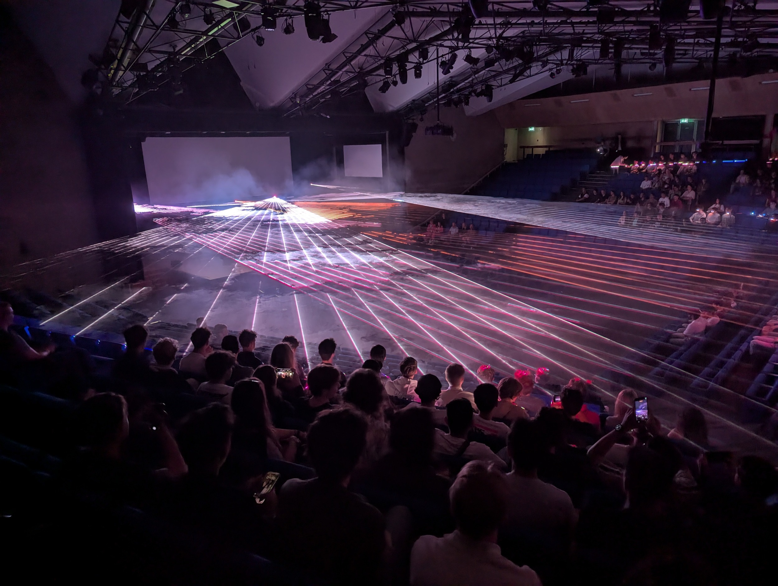 Studenten zitten in de Aula tijdens een lasershow