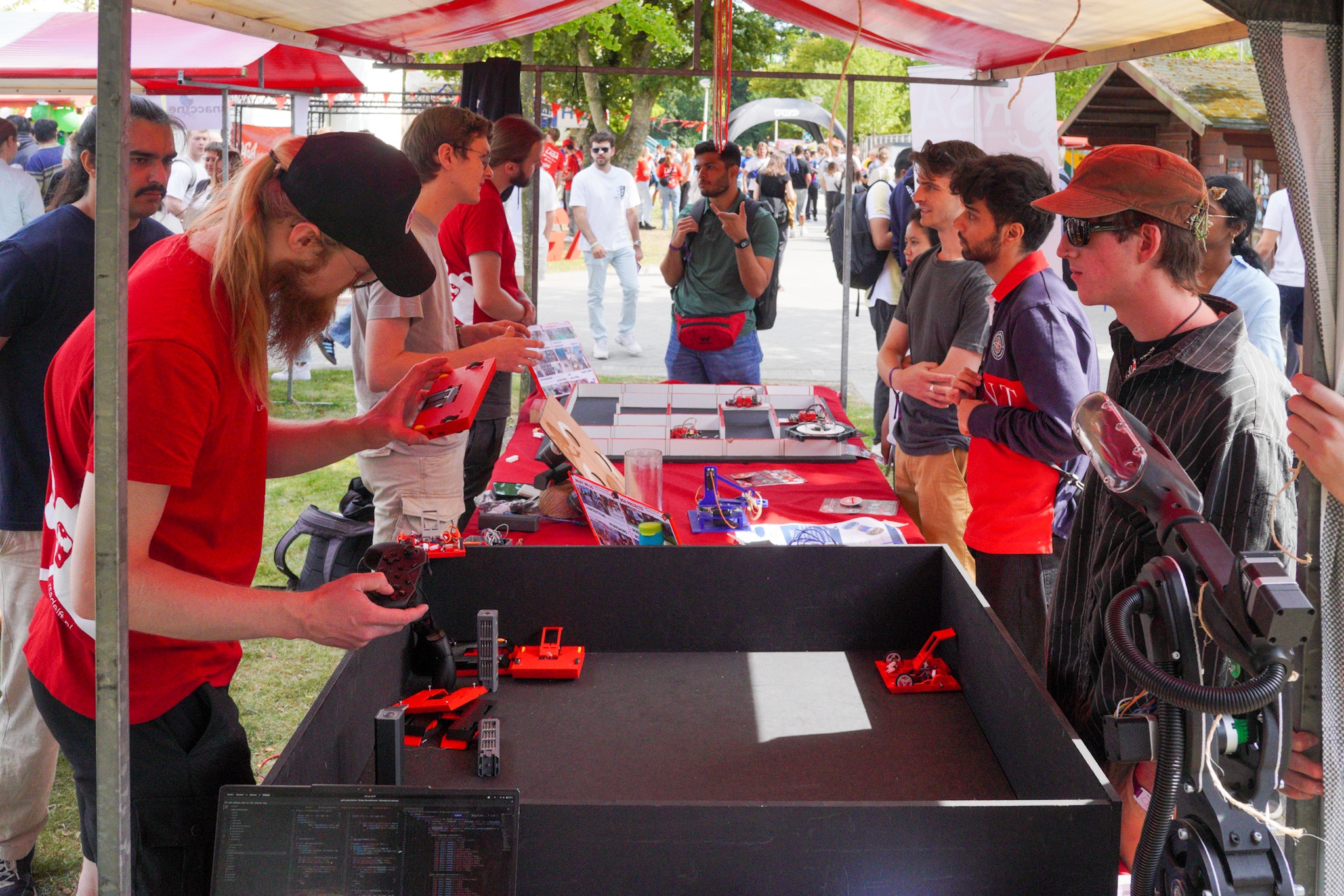 Verschillende mensen staan rond een marktkraam waarop robots te zien zijn.
