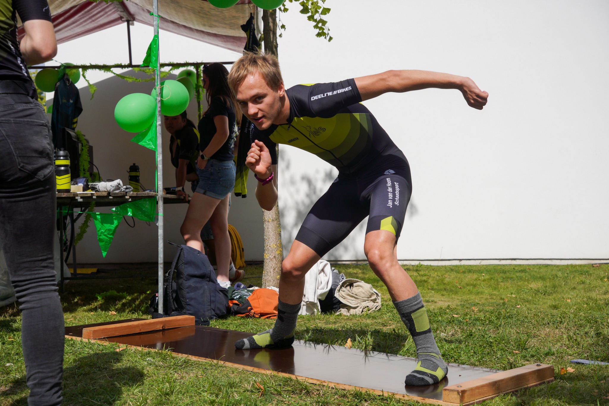 Een schaatser staat op dikke sokken op een plank terwijl hij zijn schaatsbeweging oefent.