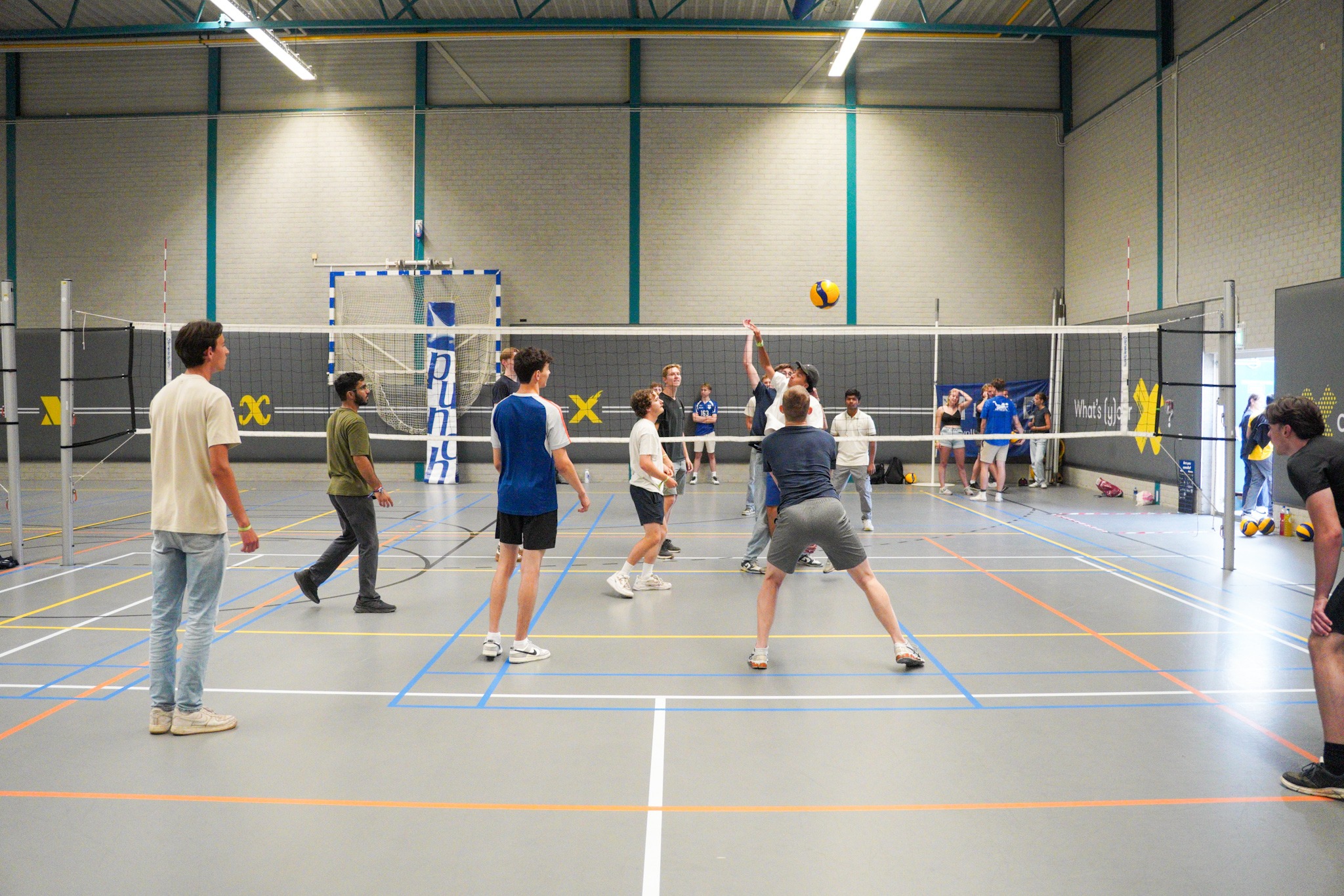 Mensen spelen volleybal in een zaal van X.