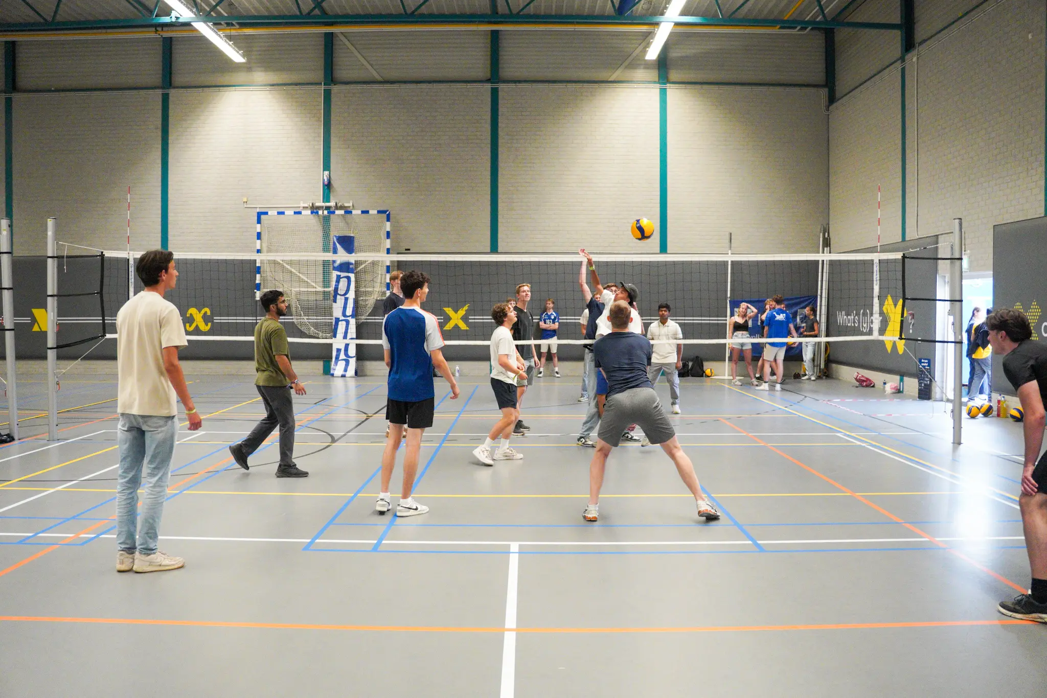 OWee_Activiteiten Markt_X (27) Mensen spelen volleybal in een zaal van X.
