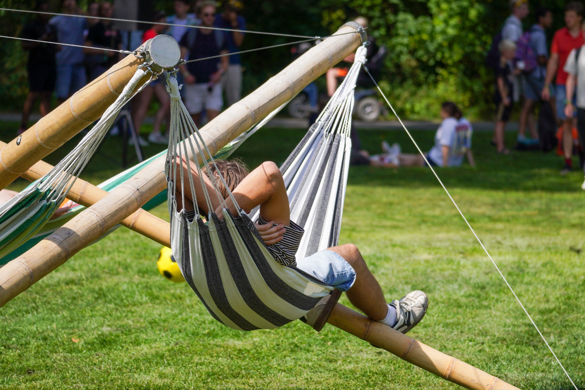 Aan een houten stellage hangt een hangmat. Daarin ligt een deelnemer van de OWee.