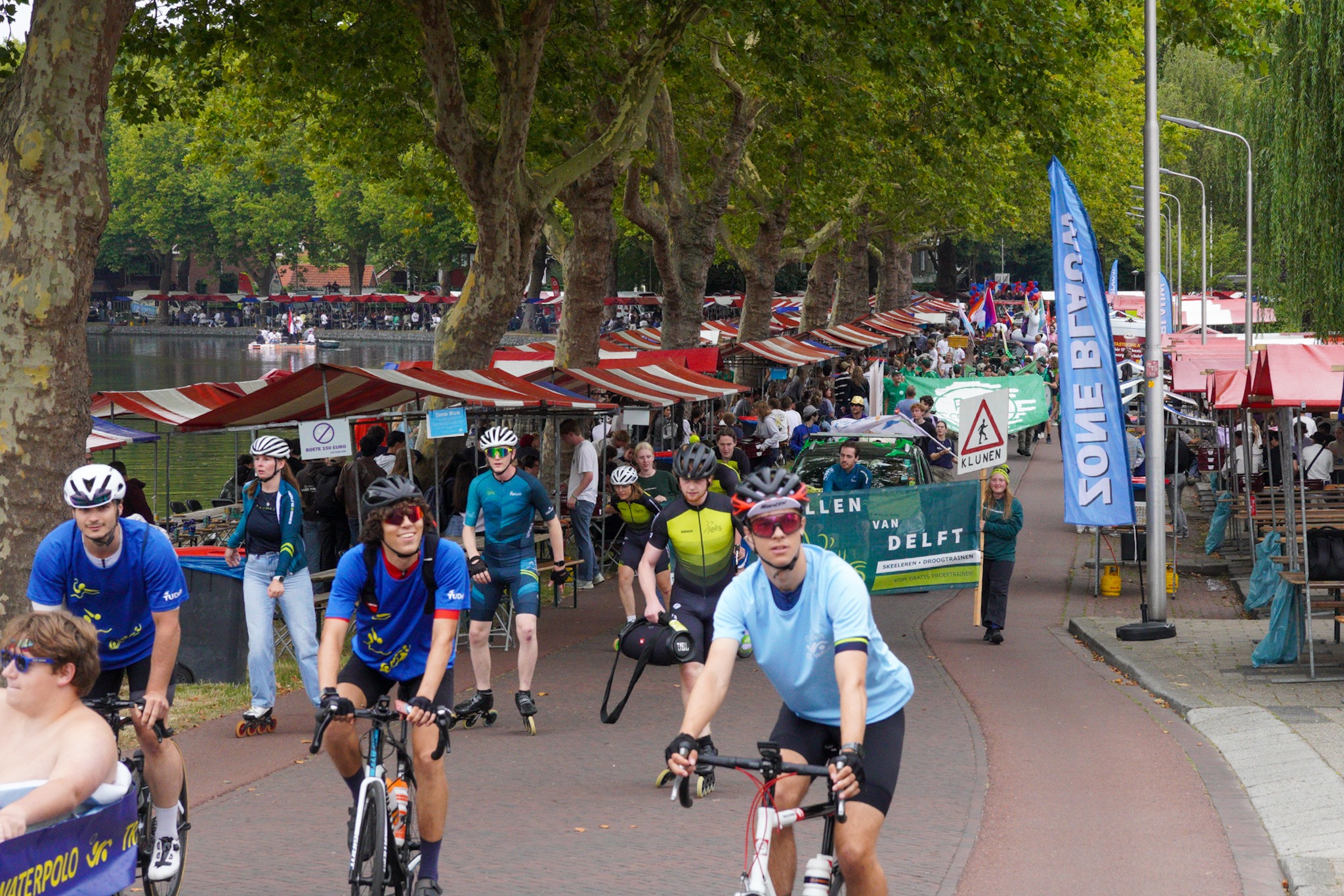 Een straat vol kraampjes en mensen, Op de voorgrond fietsers