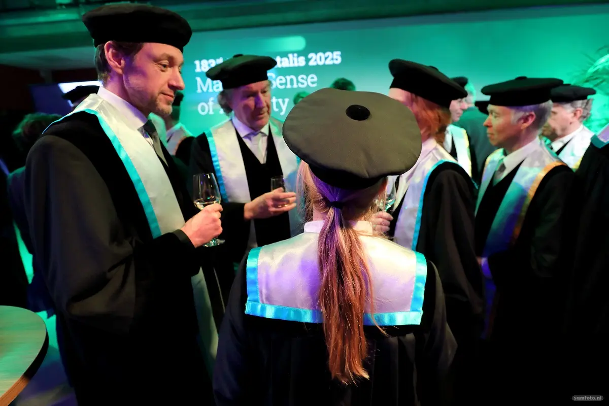 Hoogleraren in toga staan op een borrel en praten met elkaar