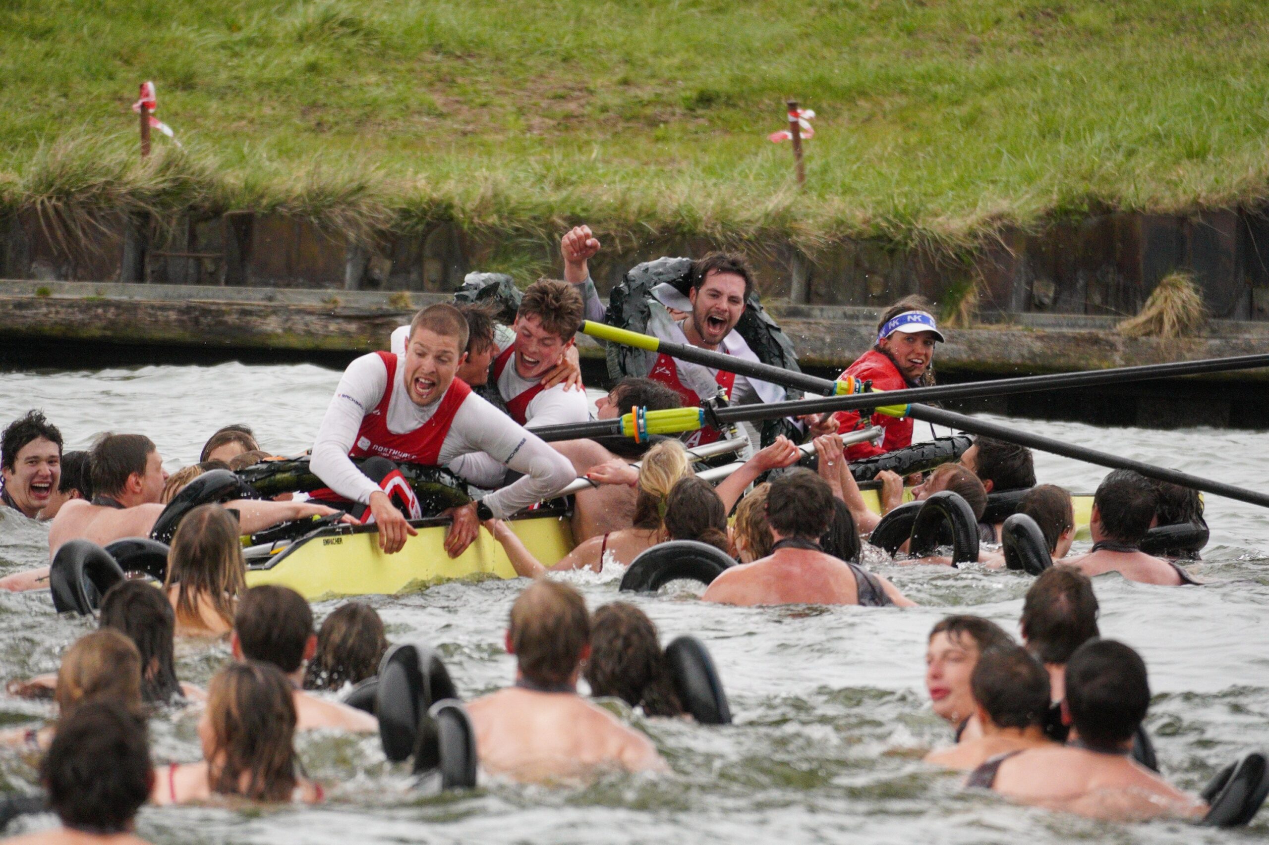 Roeiers liggen in het water. Ze juichen