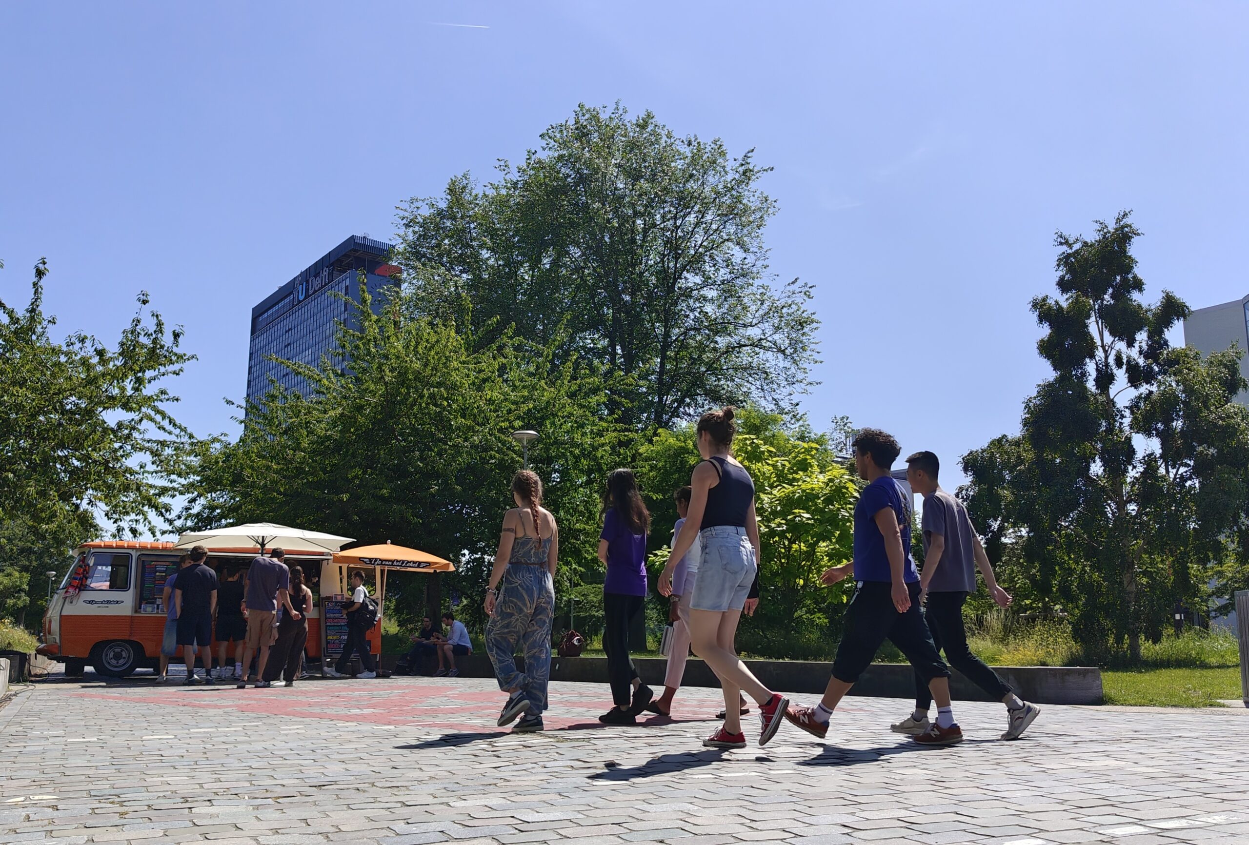 This is how TU Delft campus keeps its cool during a sweltering exam week Mensen lopen over straat in het Mekelpark.