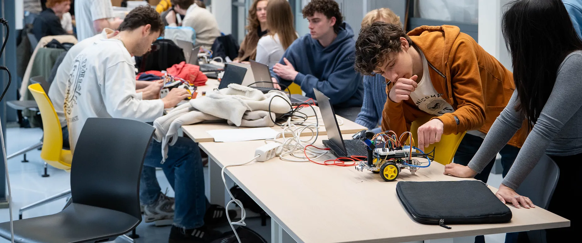 TU Delft lecturers win Dutch Education Award with robotics project Studenten zijn aan een lange tafel aan het werk