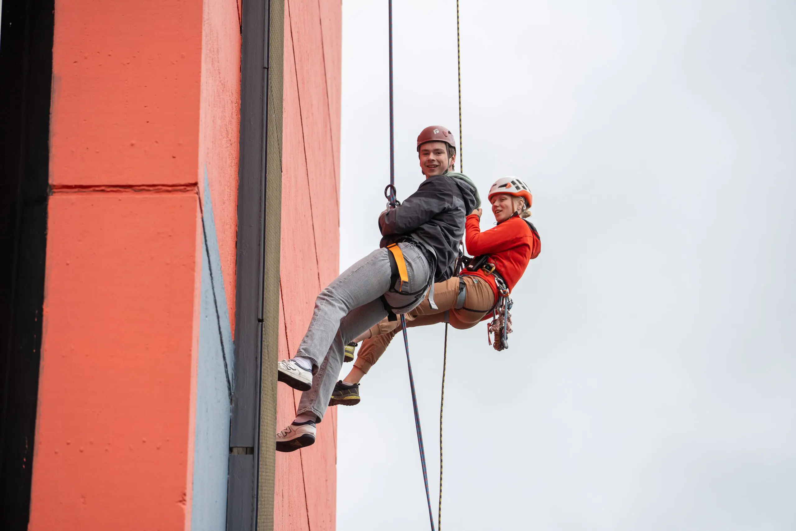 abseilers langs de EWI-toren lachen naar de camera